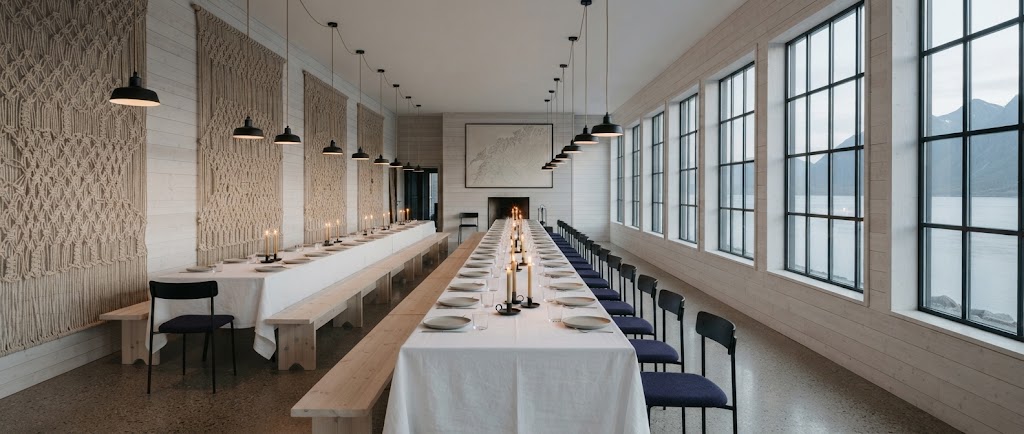 Artist's impression of a banquet in the long room: one long table with white linen and candles under a row of lamps, tall windows onto the sound